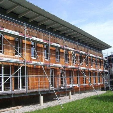 Gebäude mit einer Holzfassade, umgeben von Gerüst für anstehende Renovierungsarbeiten