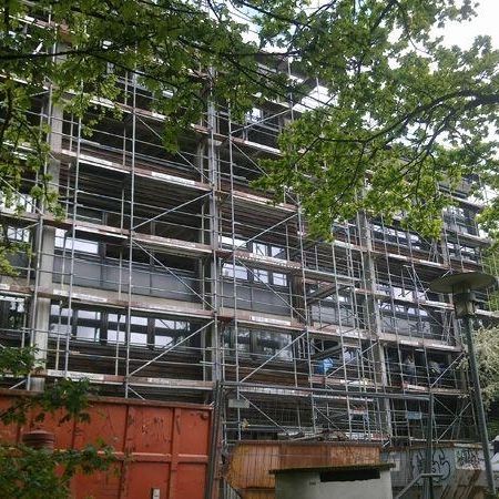 Baustelle eines Gebäudes mit Gerüst und Bäumen im Hintergrund