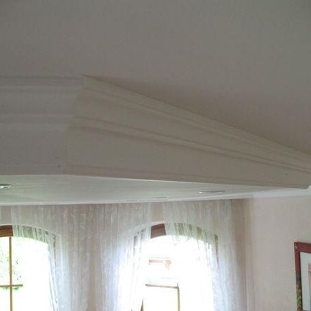 Decke mit weißen Stuckverzierungen und mehreren Fenstern