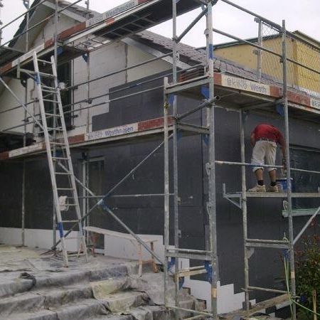 Einfamilienhaus mit Gerüst, wo gerade die Wärmedämmung angebracht wird